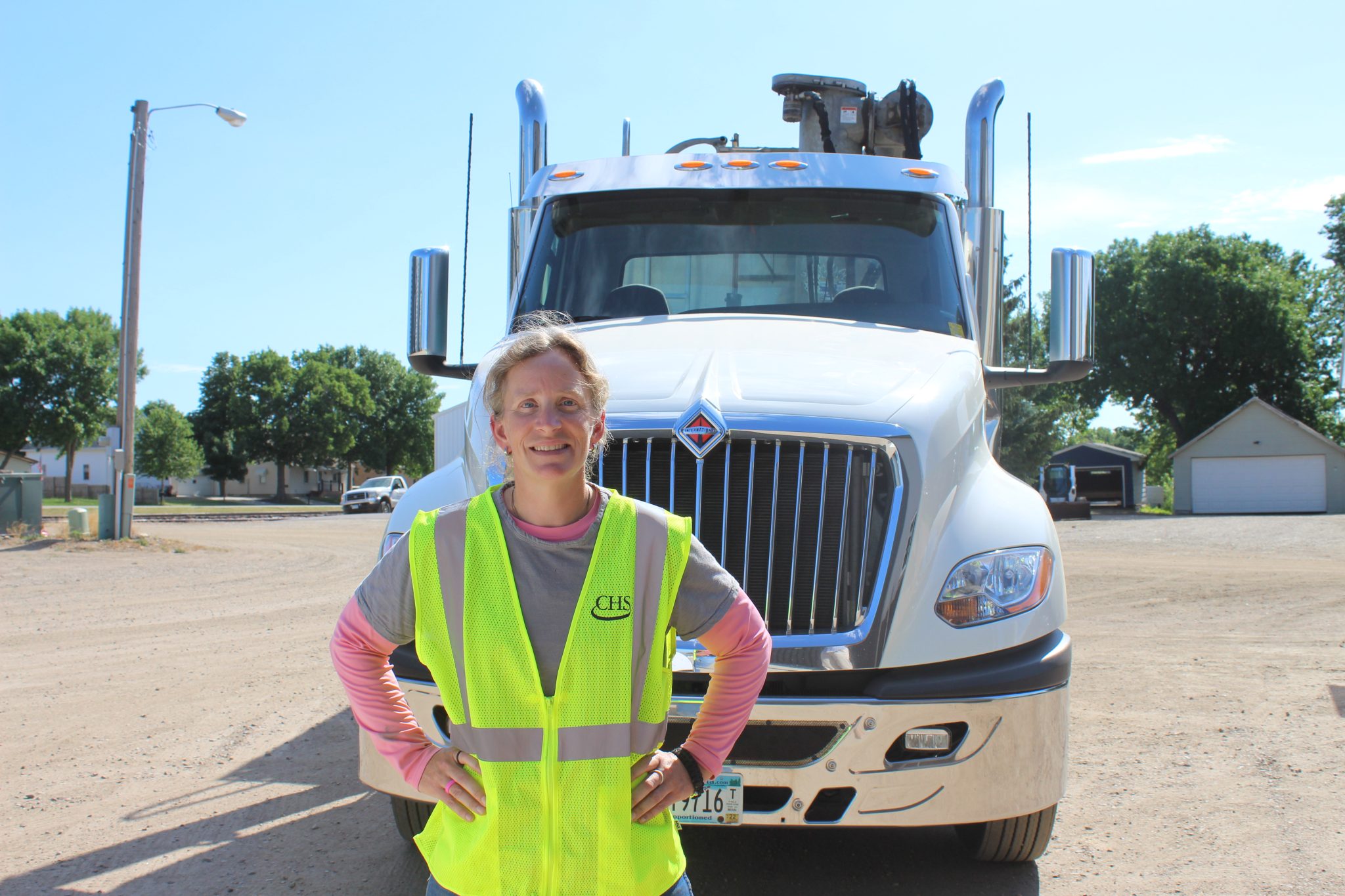 Woman wearing yellow safety vest in front of a semi truck cab