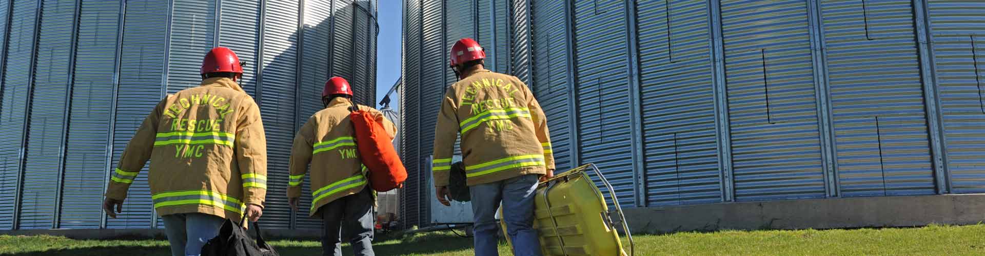 Three firefighters wearing PPE walking towards grain bins