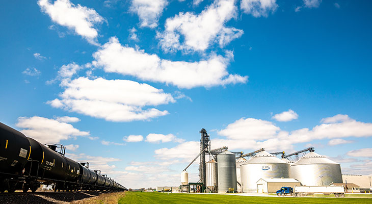 Grain bins beside a railroad track under a cloudy blue sky